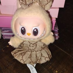 Labubu plush doll wearing a brown designer-style dress and bow accessor