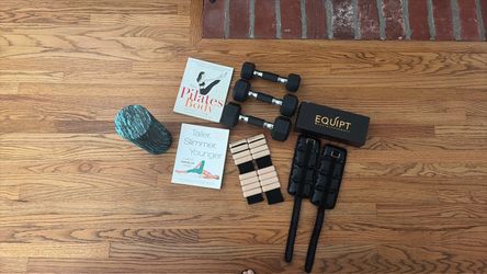 Workout wrist weights, dumbbells, foam roller with accompanying book, and Pilates book