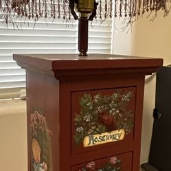 Decorative lamp with a fringed- jeweled shade featuring small pull drawers w hand painted lettering/herb shrubbery and girl & boy on side of 