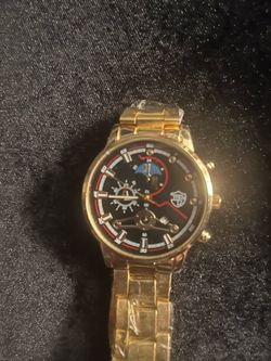 New gold men watch. Has black dial with multiple subdials. Watch has moon phase indicator. Metal link band is gold color. Protective film is on watch.