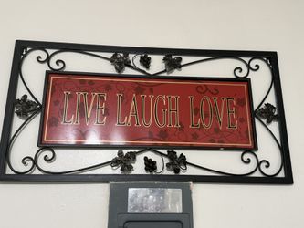A Steel Sign With Black Edges And With Red And Black With Gold Lettering Quote