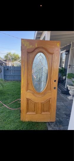 Solid oak wood door has a large oval leaded glass insert with a floral motif. This exterior door is pre-drilled for a handle and deadbolt. The wood ha