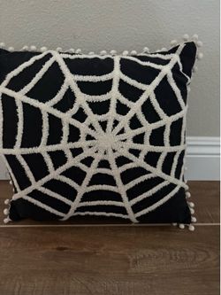 Haunted Living 16-inch black spider web throw pillow with white embroidered details and pom-pom trim