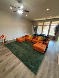 Orange Sectional with free rug , couch pillows , and plants