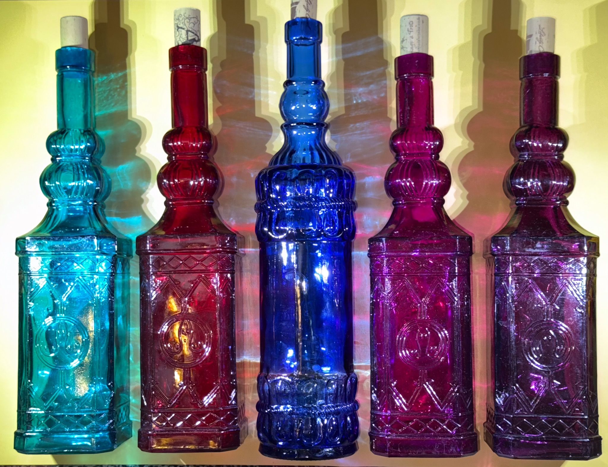Five glass decanters features a raised design on both the front and back, adding a touch of elegance to any bar or collection