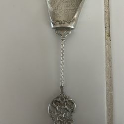 antique or vintage silver sugar spoon, likely of Dutch or German origin, with an ornate handle and a scoop-style bowl featuring engraved animal imager
