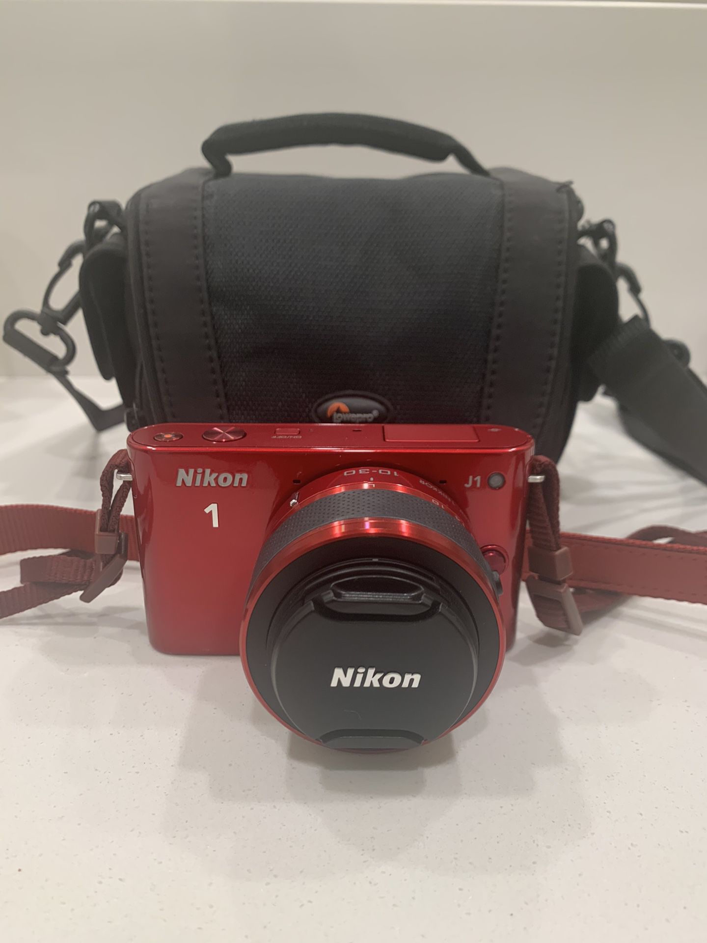 Red Nikon 1 camera with zoom in lens and bag