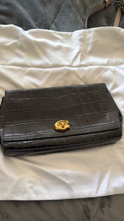 This Coach Alexa Turnlock Clutch is crafted from black crocodile-embossed leather and features the signature polished turnlock closure.