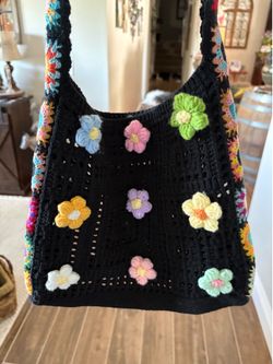 handmade black crochet shoulder bag features colorful 3D flower appliques and a vibrant floral granny square strap
