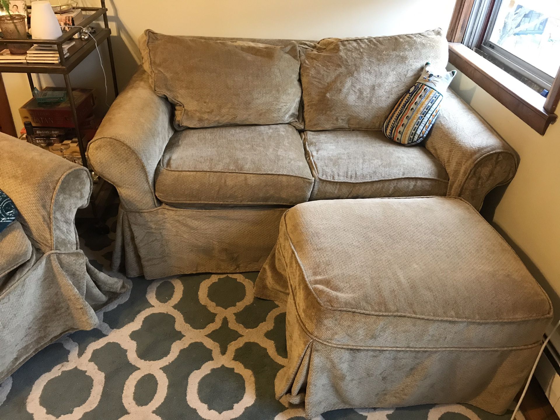 White pottery barn love seat and ottoman with slip covers.
