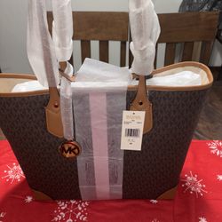 Michael Kors Eva Large Signature Logo Stripe Tote Bag in brown with a pink and burgundy center stripe.