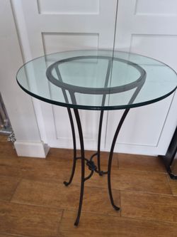 Knot pedestal table featuring a black wrought iron base and a round glass top.Brand: Pier 1 ImportsDimensions: Approximately 28" tall with a 19" diame
