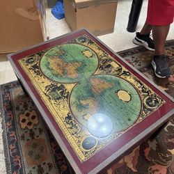 Vintage campaign-style coffee table featuring a glass top over a 17th-century style world map