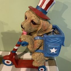 12 Inches Tall Dog On Scooter Decoration In Patriotic Colors. Dog Has Backpack That Can Hold A Small Succulent Or Plant. 