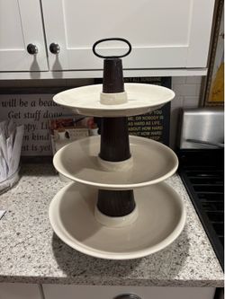 three-tiered serving tray with cream-colored plates* and dark brown wooden center columns…. bottom…*see second photo the bottom tier has been repaired