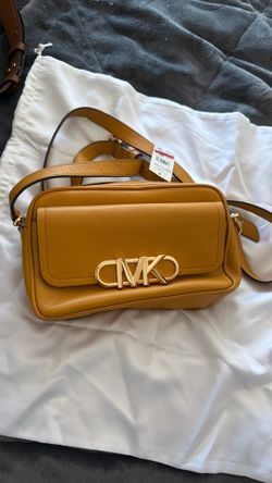 This mustard yellow leather Michael Kors bag features a prominent gold-tone signature logo clasp.