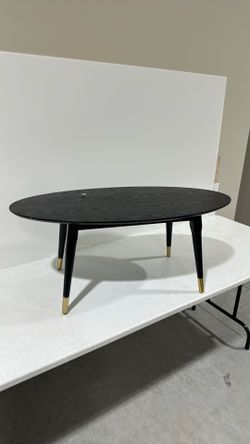 Black oval coffee table with gold accent feet