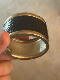 gold-tone hinged bangle bracelet with a textured black snake- or crocodile-embossed inlay, resembling designs from brands like Kenneth Cole and simila