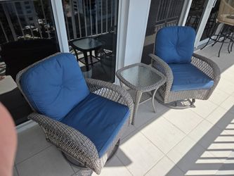Like new swivel outdoor patio chairs (2) and table.  Grey wicker with blue cushions.
