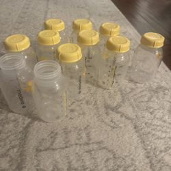 Collection of Medela bottles featuring yellow caps. Ideal for feeding and storage. Two without caps. 5 oz bottles.