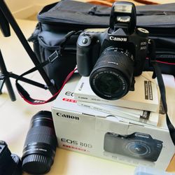 Canon D80 camera in excellent working condition. Includes a pocket printer, multiple lenses, and a camera tripod. Price: $750. 