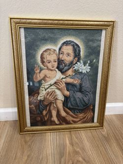 Ornate framed tapestry piece depicts Saint Joseph holding the Child Jesus