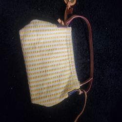 This is a vintage Dooney & Bourke fabric bag with a yellow and white striped pattern and leather trim. 