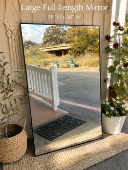 large, full-length rectangular floor/leaning mirror with a thin black frame