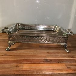 This item is a silver-colored holder for a baking dish (typically made of Pyrex-style glass), designed for elegantly serving food directly from the ov