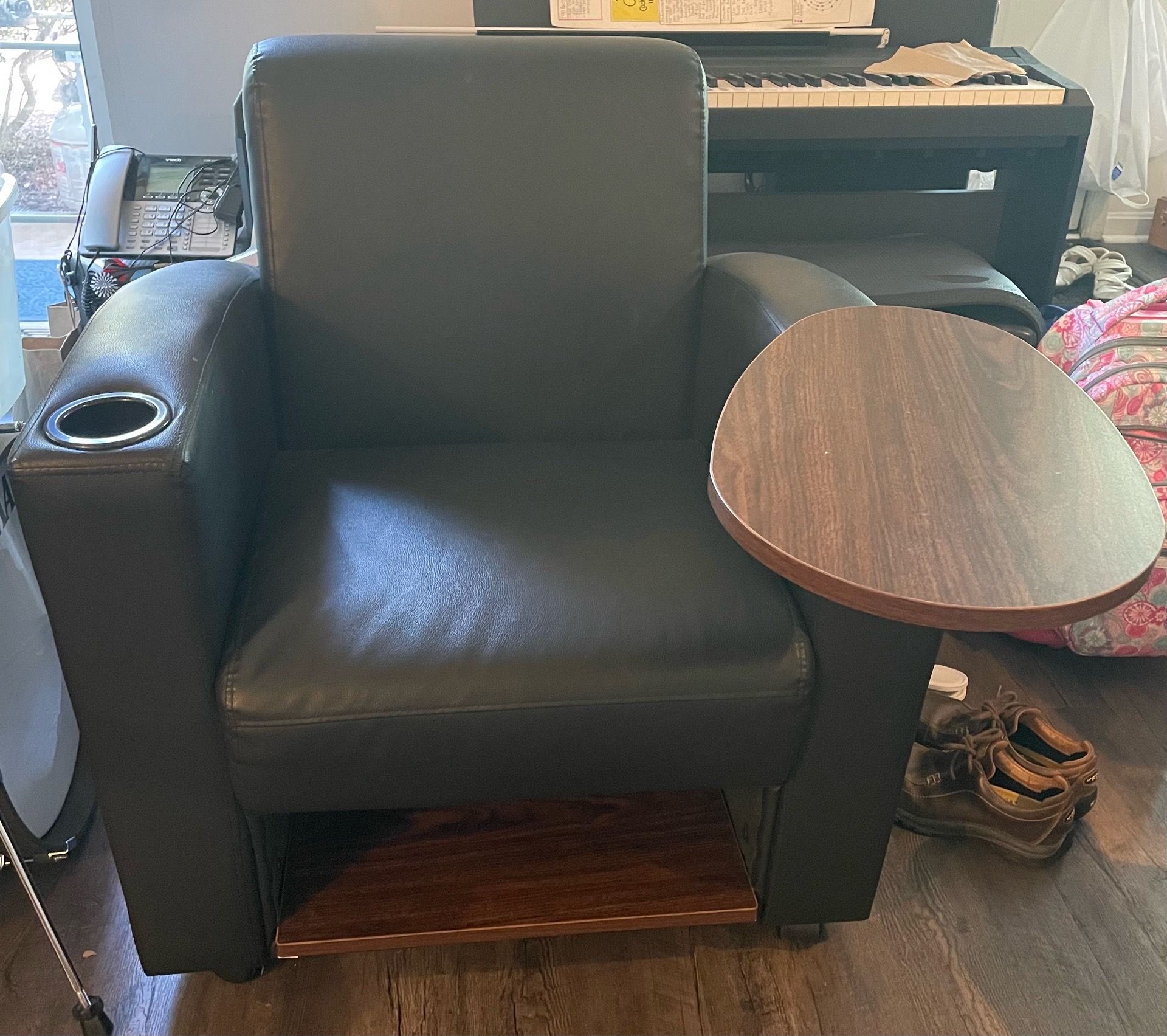 Black arm chair with swinging table and storage.
