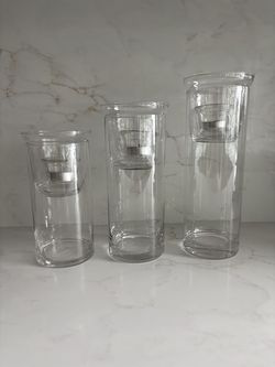 Set of three clear glass cylinder hurricane candle holders.