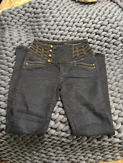 High-rise women's jeans with decorative gold-tone button accents.