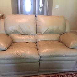 Italian leather reclining sofa and loveseat, coffee table 2 end tables with lamps and a area rug.