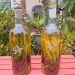 PAIR OF ORNAMENTAL BOTTLES FILLED WITH VEGGIES INFUSED IN OLIVE OIL .