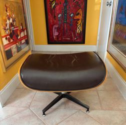 Eames Lounge Ottoman Reproduction in brown leather and wooden shell. It has some chips in wood. Available in Coral Gables.