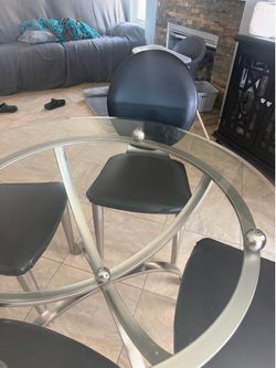 Round glass dining table with 4 chairs.