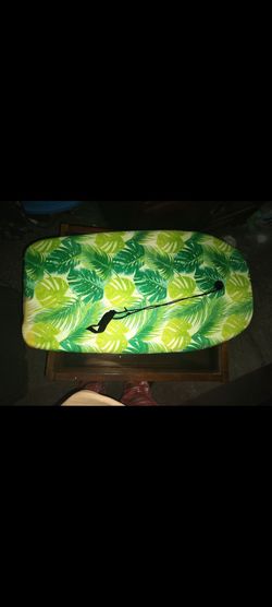 Boogie board with a vibrant green tropical leaf pattern and includes a black leash