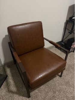 This is a Signature Design by Ashley Peacemaker mid-century modern brown faux leather accent chair with a black metal frame