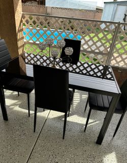 A glass dining table with four leather chairs.    😀😀😀