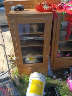 This image shows a light wood display cabinet with a glass door and a small lower drawer.