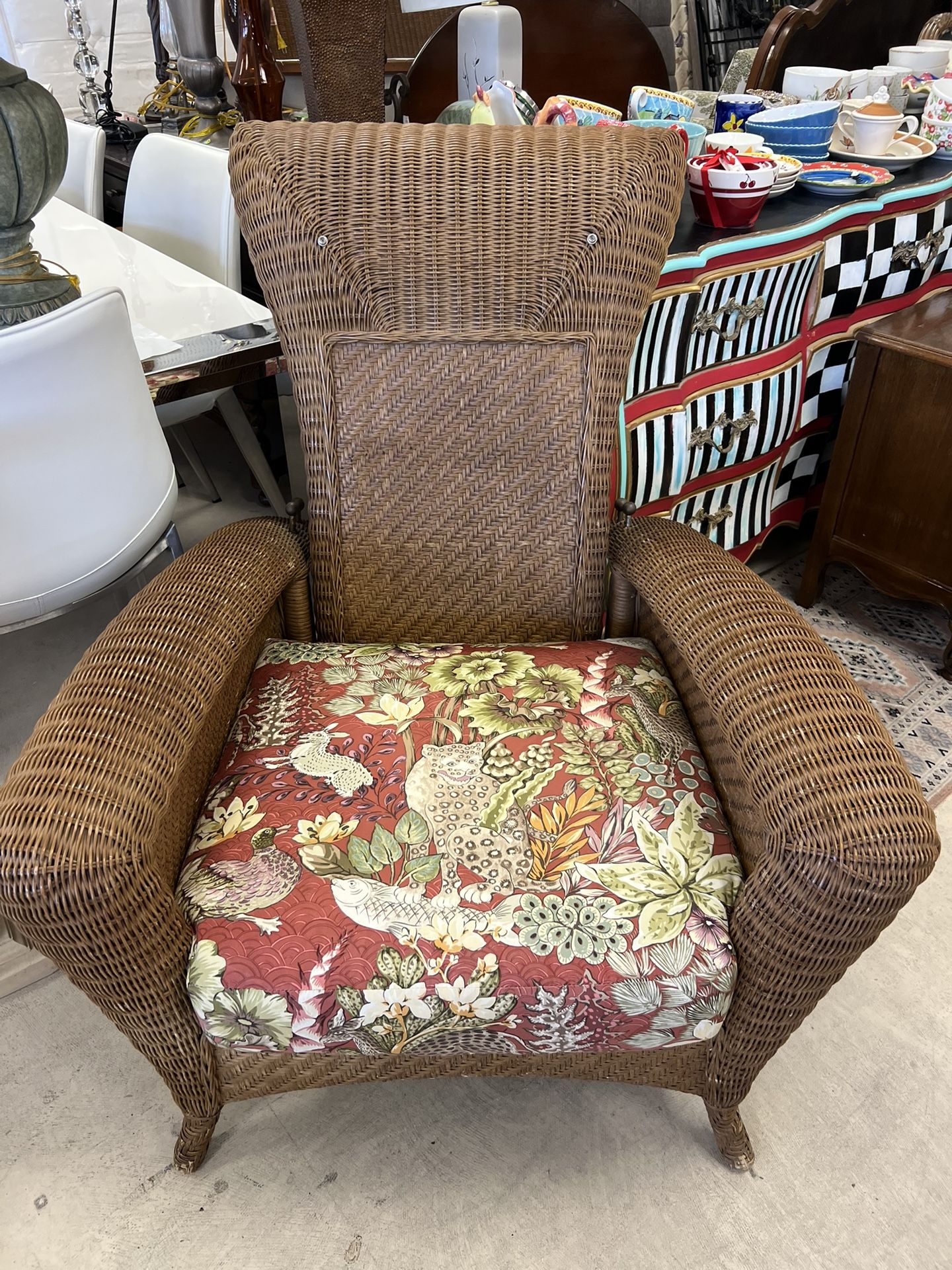 brown woven wicker or rattan armchair with a floral cushion