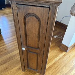 Tall narrow solid wood cabinet with a classic arched-panel door and rich dark finish.