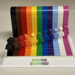 This is the LEGO Everyone Is Awesome set (40516) displayed inside a clear acrylic showcase.The set features 11 monochrome minifigures arranged on a st