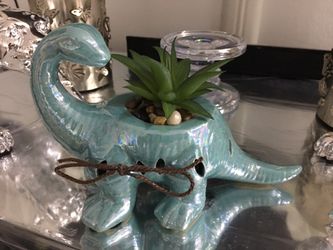 Dinosaur figurine with artificial succulent plant.
