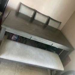 Una mesa con tres sillas y un banco