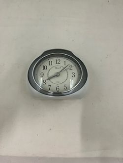 analog alarm clock with a modern oval or tear-drop shape.