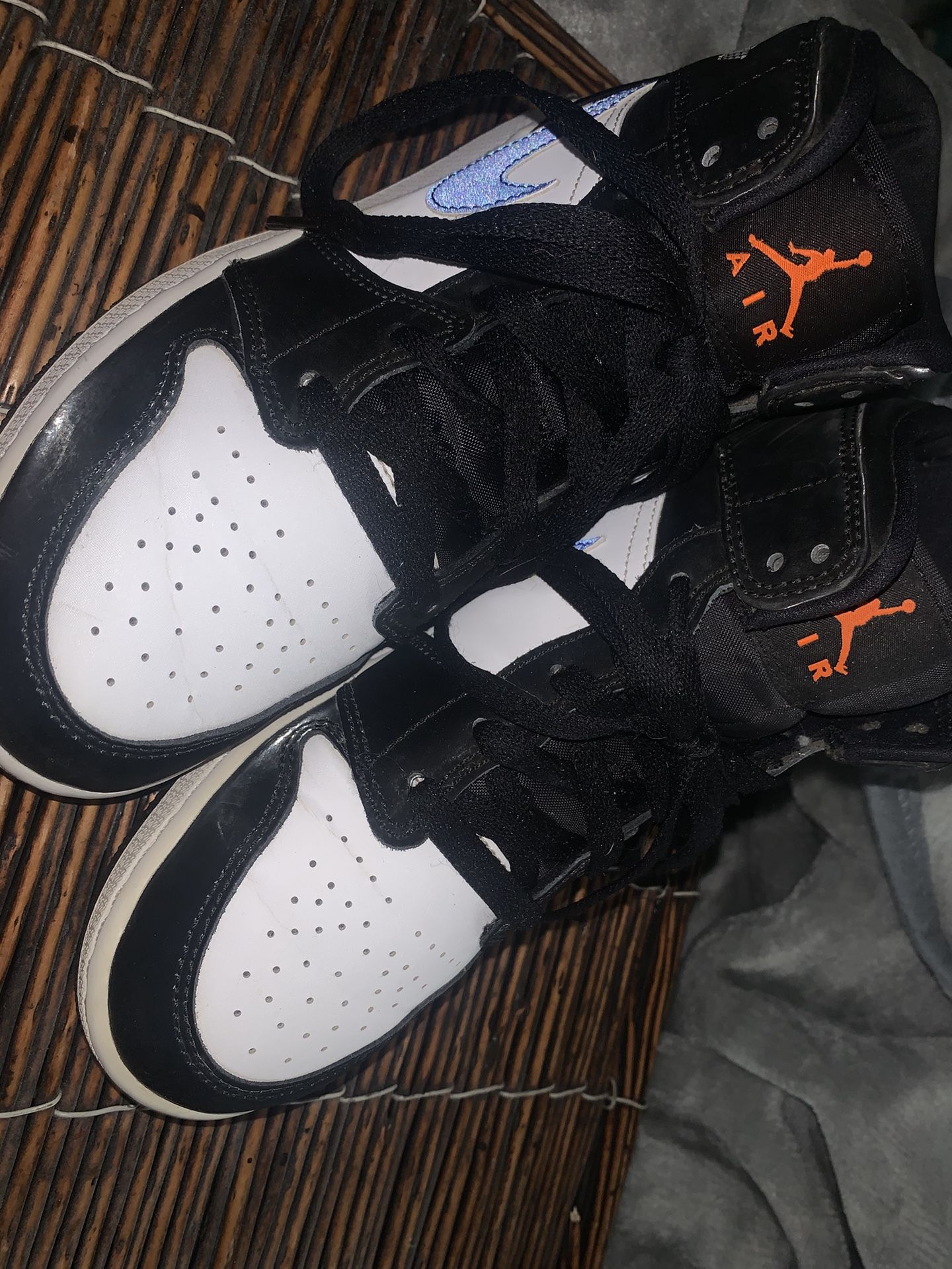 The grade school Jordan 1 Mid Black Racer Blue White (GS) features a black synthetic upper with white leather overlays in the center and forefoot.