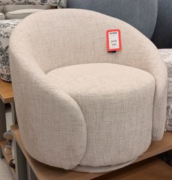 modern barrel-style swivel accent chair upholstered in a cream or ivory textured wove