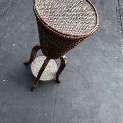 Vintage wicker and rattan plant stand with tripod legs.