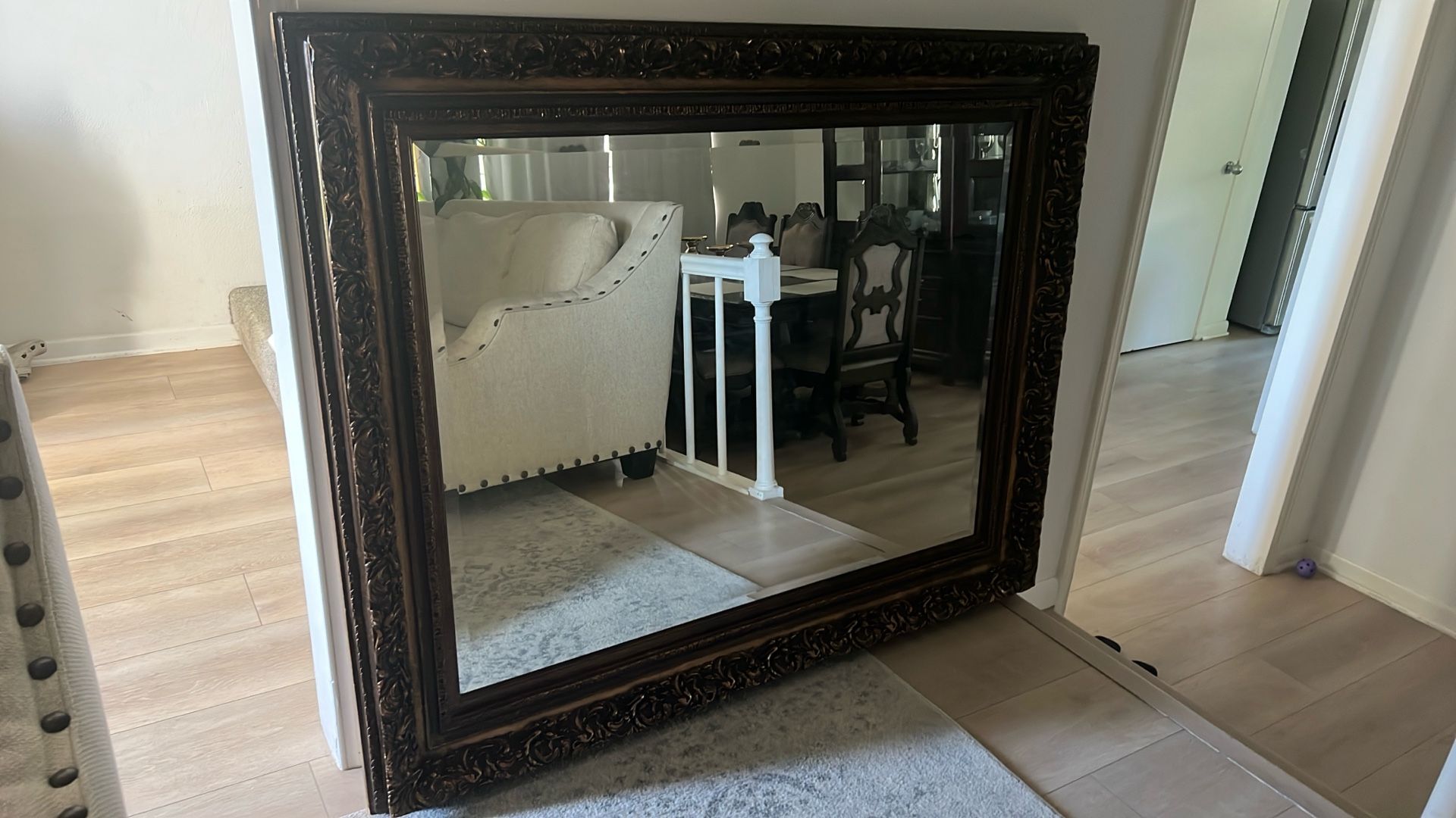 This is a large, ornate vintage mirror, likely featuring a gold or bronze-colored frame with intricate carvings